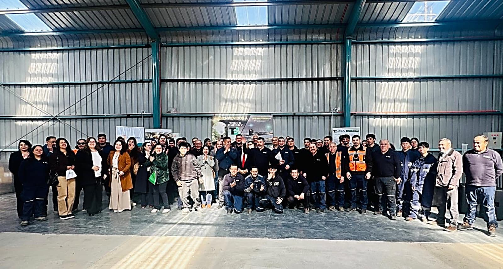 Alrededor de cincuenta personas posando juntas en un galpón durante la firma de la alianza con el CFT de Lota y Arauco, con un pendón de Truck Energy al fondo
