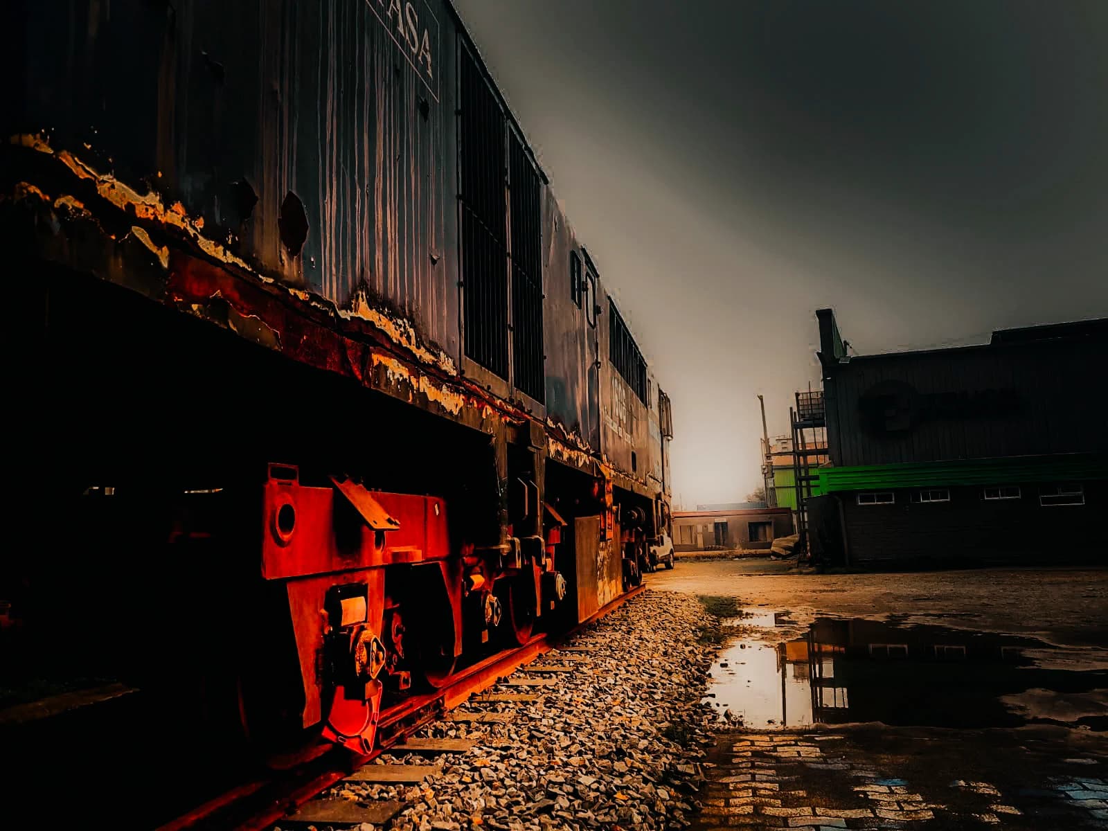 Locomotora del Ferrocarril del Pacífico detenida sobre la vía en el patio de Truck Energy en Coronel, con la carrocería carcomida por el óxido y el galpón de la empresa al fondo