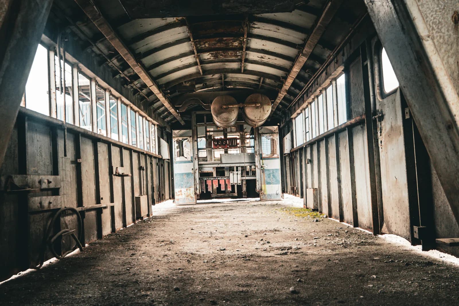 Interior de un carro ferroviario abandonado, con las ventanas rotas y el piso cubierto de escombros