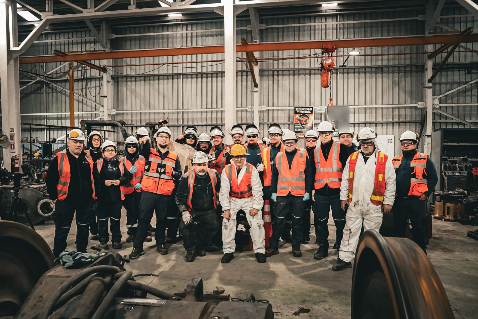 Equipo de Truck Energy reunido en el taller de Coronel, con un par montado y carcasas de motor de tracción en primer plano y el puente grúa al fondo