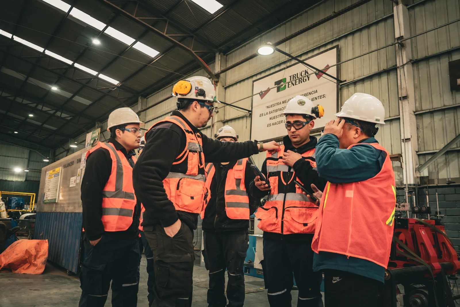 Grupo de técnicos de Truck Energy y el ingeniero visitante conversando de pie en el taller durante la revisión de procesos