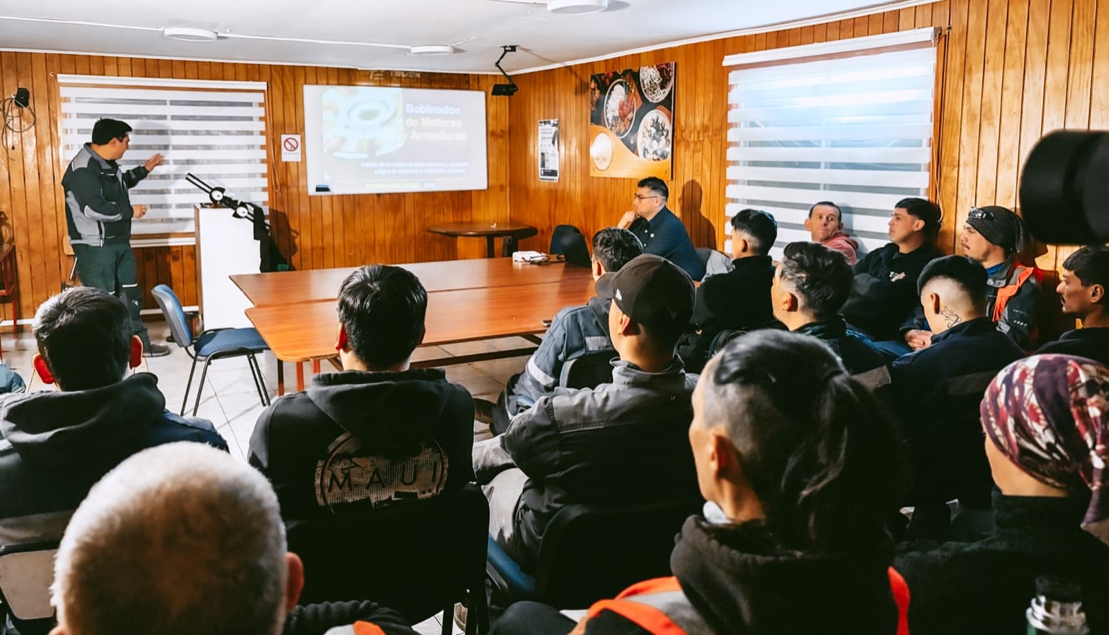 El expositor señalando la lámina proyectada mientras la sala llena sigue la explicación