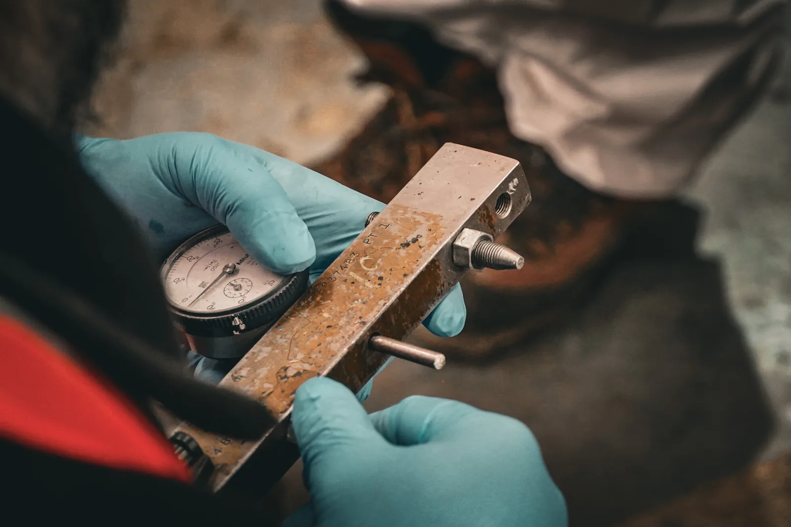 Dial indicator measurement on a machined surface, taken with nitrile gloves during dimensional diagnosis