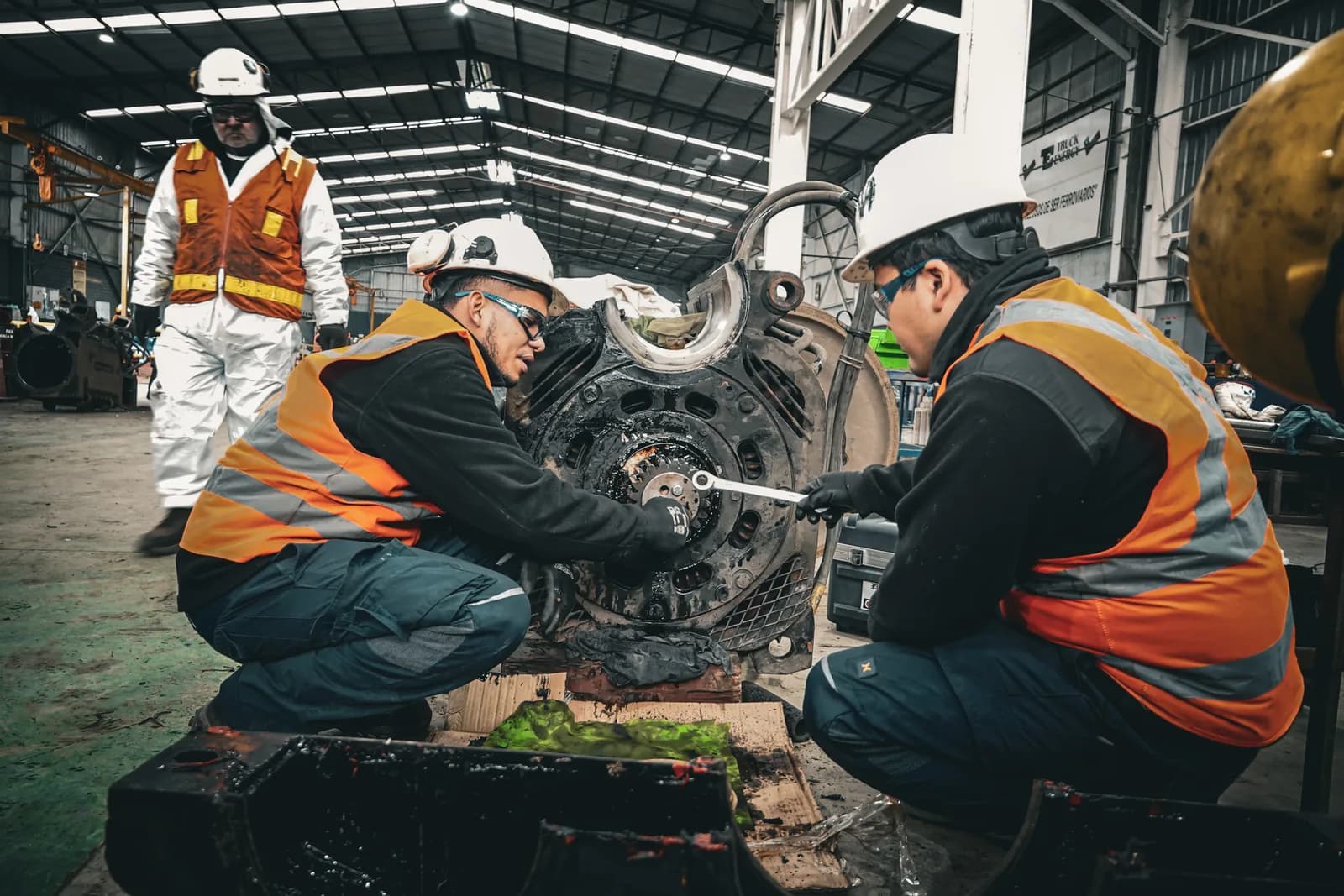 Two Truck Energy technicians kneeling as they work on a stripped traction motor on the floor of the Coronel workshop